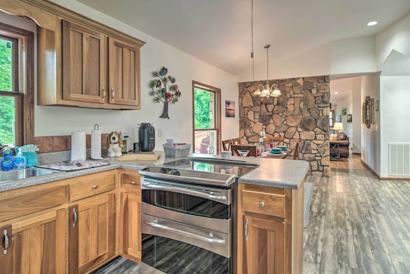 A modern kitchen with wooden cabinets, a built-in oven, and a stone accent wall.
