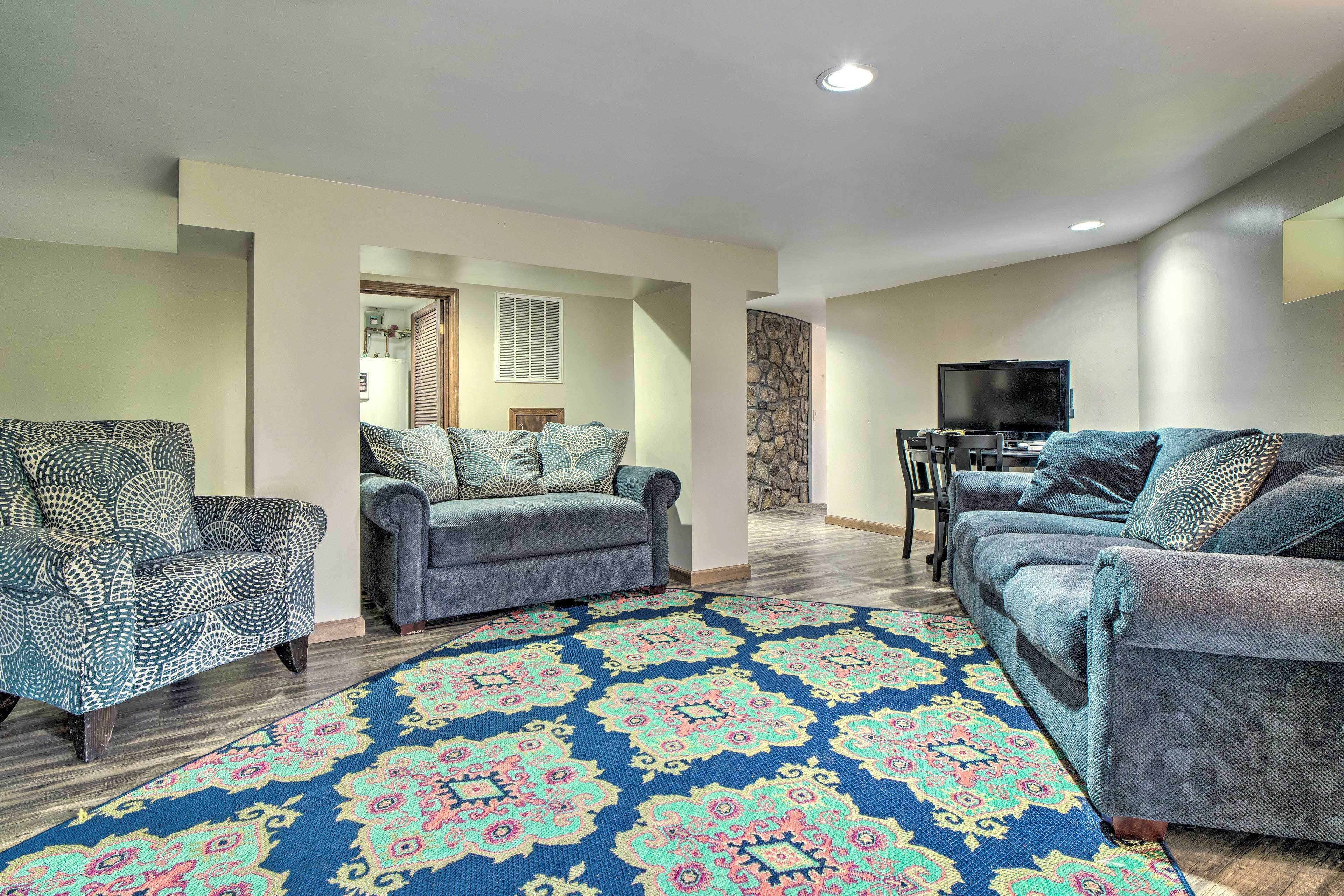 A living room with two sofas, a patterned rug, and a television.