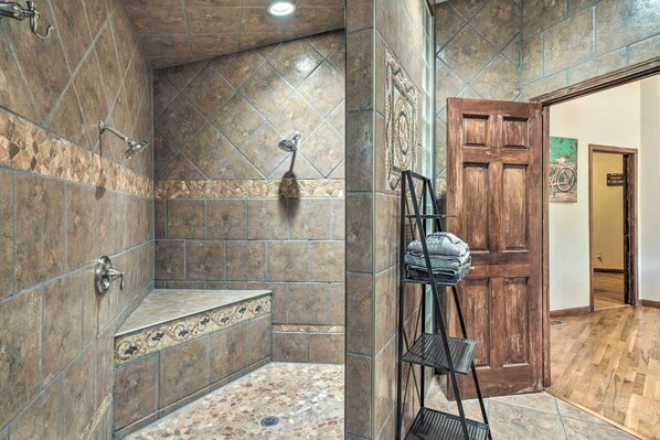 A bathroom with a shower, a bench, and a wooden door.