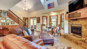 A spacious living room with leather sofas, a fireplace, and a staircase leading to another room. - 'troutfest' Riverfront Norfork Home, Great Fishing (Norfork)