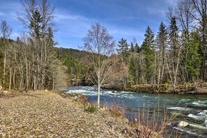 A river flowing through a forested area with trees and a clear sky.