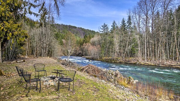 A riverside setting with a table and chairs, surrounded by trees and a forested area. - Remote Escape: Riverside Home w/ Scenic Views (Idanha)