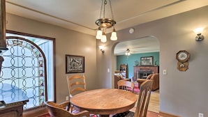 A dining area with a round wooden table, wooden chairs, and a stained glass window. - Remote Escape: Riverside Home w/ Scenic Views (Idanha)