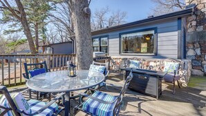 An outdoor patio with a glass table, chairs, and a stone wall.