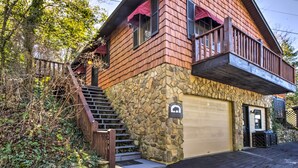 A two-story stone house with a stone facade, a wooden balcony, and a garage. - Quaint Bryson City Cottage w/ Smoky Mountain Views (Bryson City)