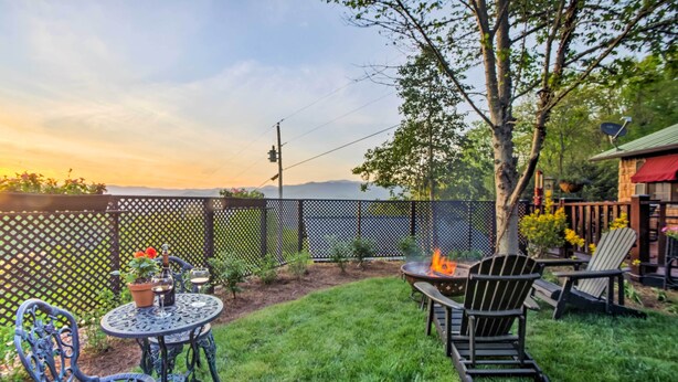 A patio with a round table and chairs, a fire pit, and a view of the sunset. - Quaint Bryson City Cottage w/ Smoky Mountain Views (Bryson City)