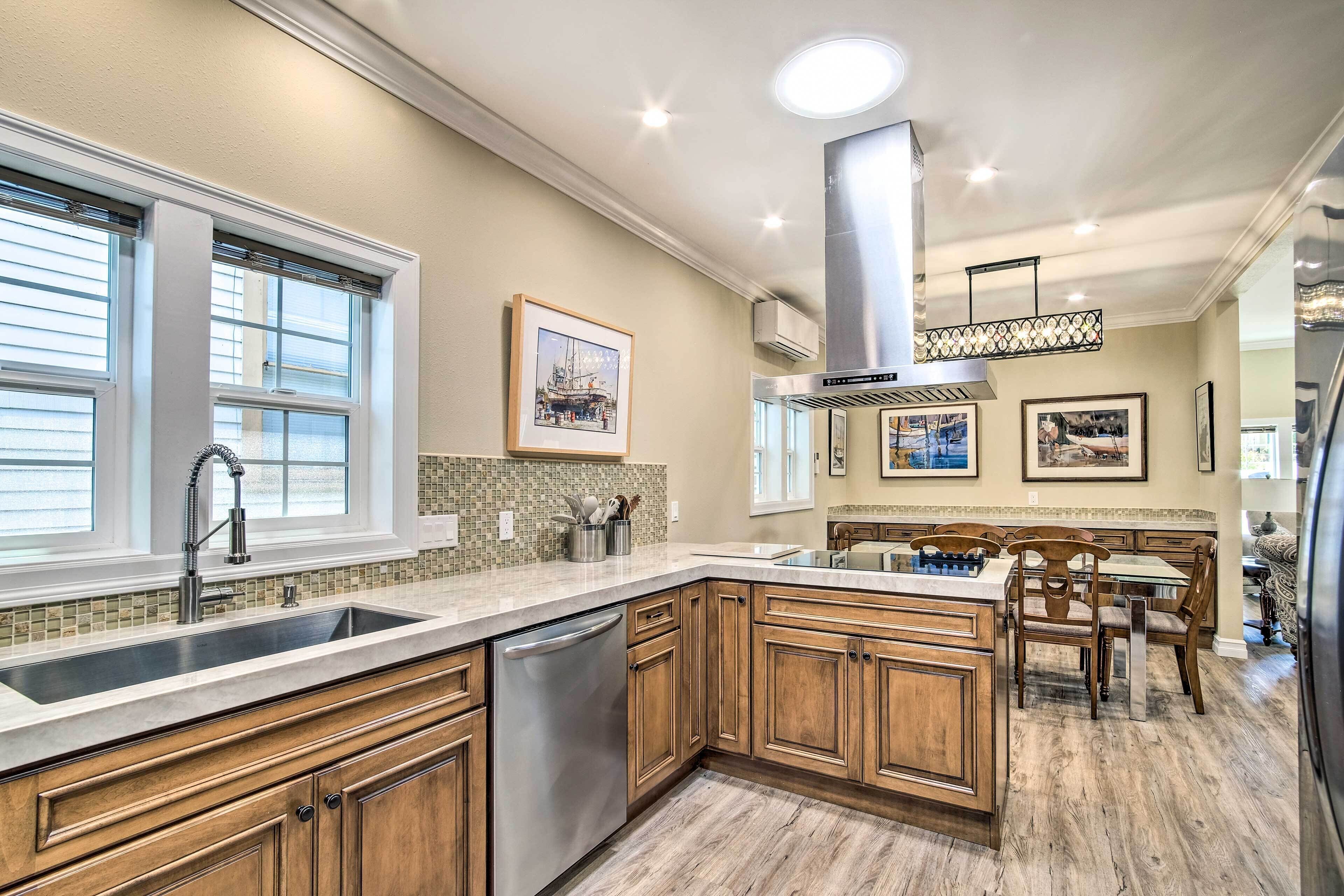 A kitchen with wooden cabinets, a stainless steel dishwasher, a tiled backsplash, and a dining area with a table and chairs.