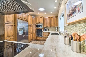 Una cocina moderna con armarios de madera, electrodomésticos de acero inoxidable, una isla grande y un salpicadero de azulejos.