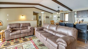 A spacious living room with two leather sofas, a dining area with a table and chairs, and a kitchen area with cabinets. - Breezy Point House w/ Dock on Pelican Lake! (Pequot Lakes)