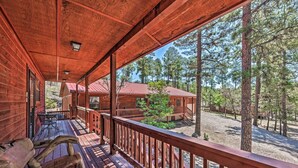 A wooden cabin with a porch, outdoor seating, and a view of surrounding trees. - Wooded Ruidoso Hideaway w/ Deck: Ski, Hike & Golf! (Ruidoso)