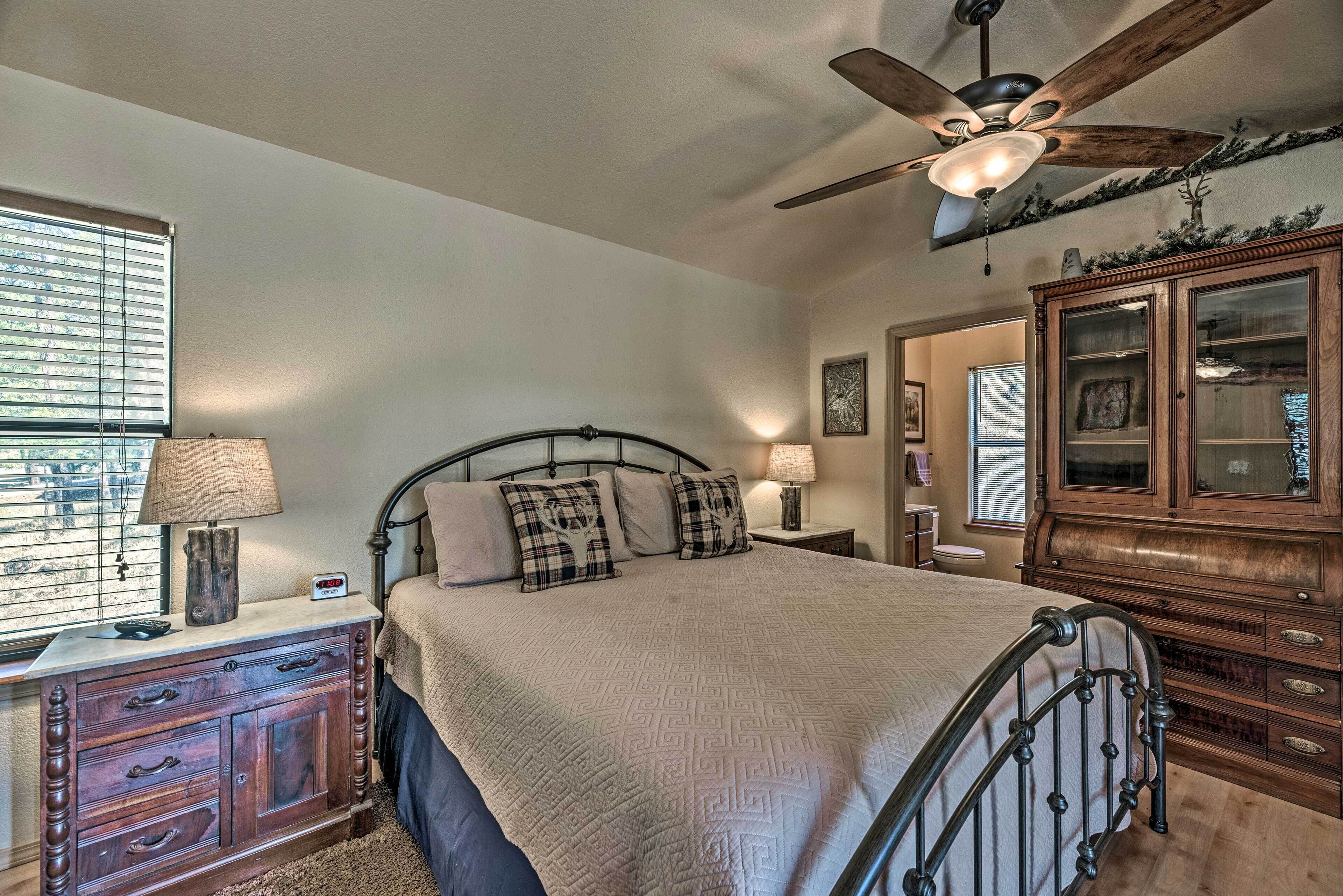 A bedroom with a bed, a dresser, a ceiling fan, and a window with blinds.