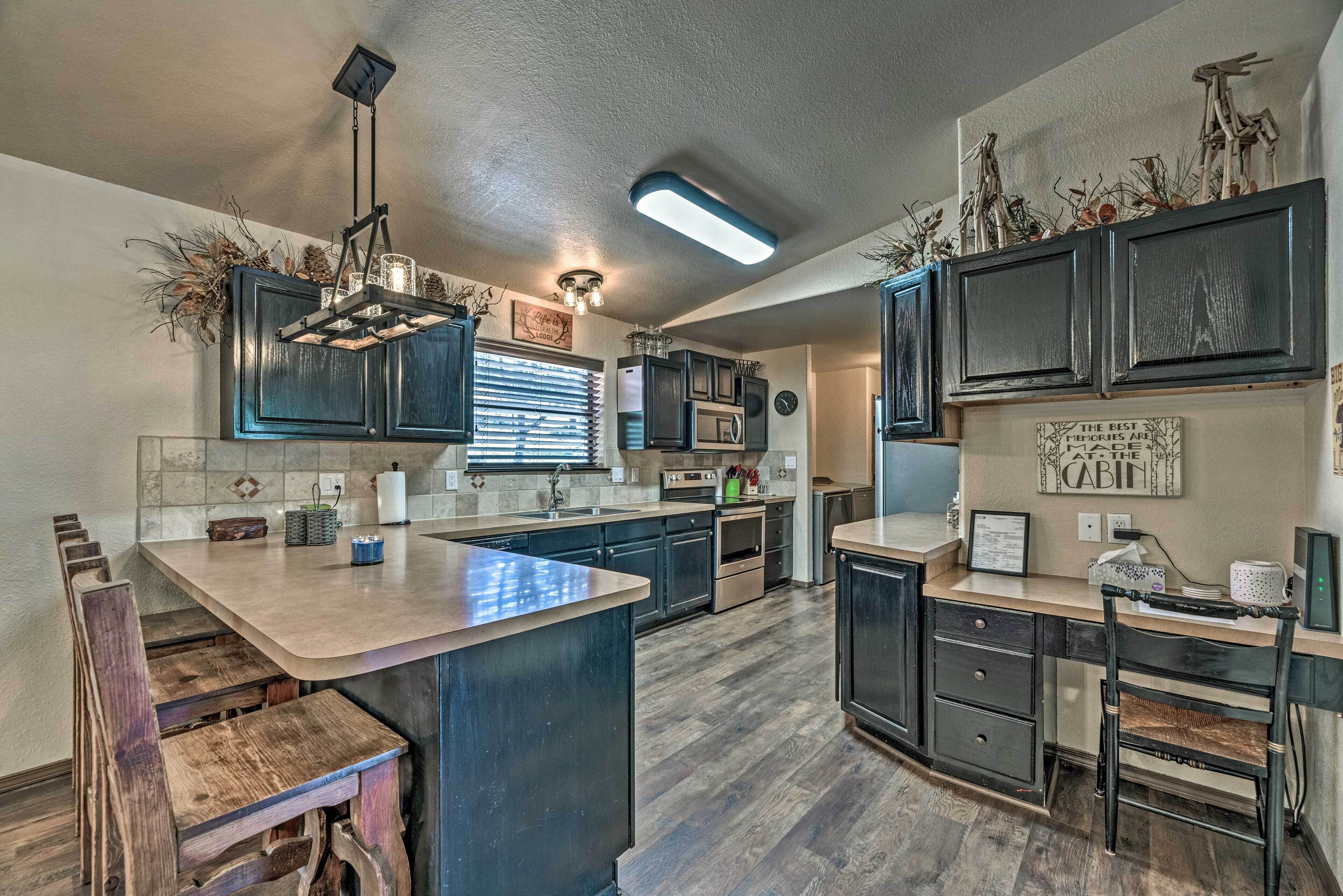 A modern kitchen with dark cabinetry, a central island, and a hanging light fixture.
