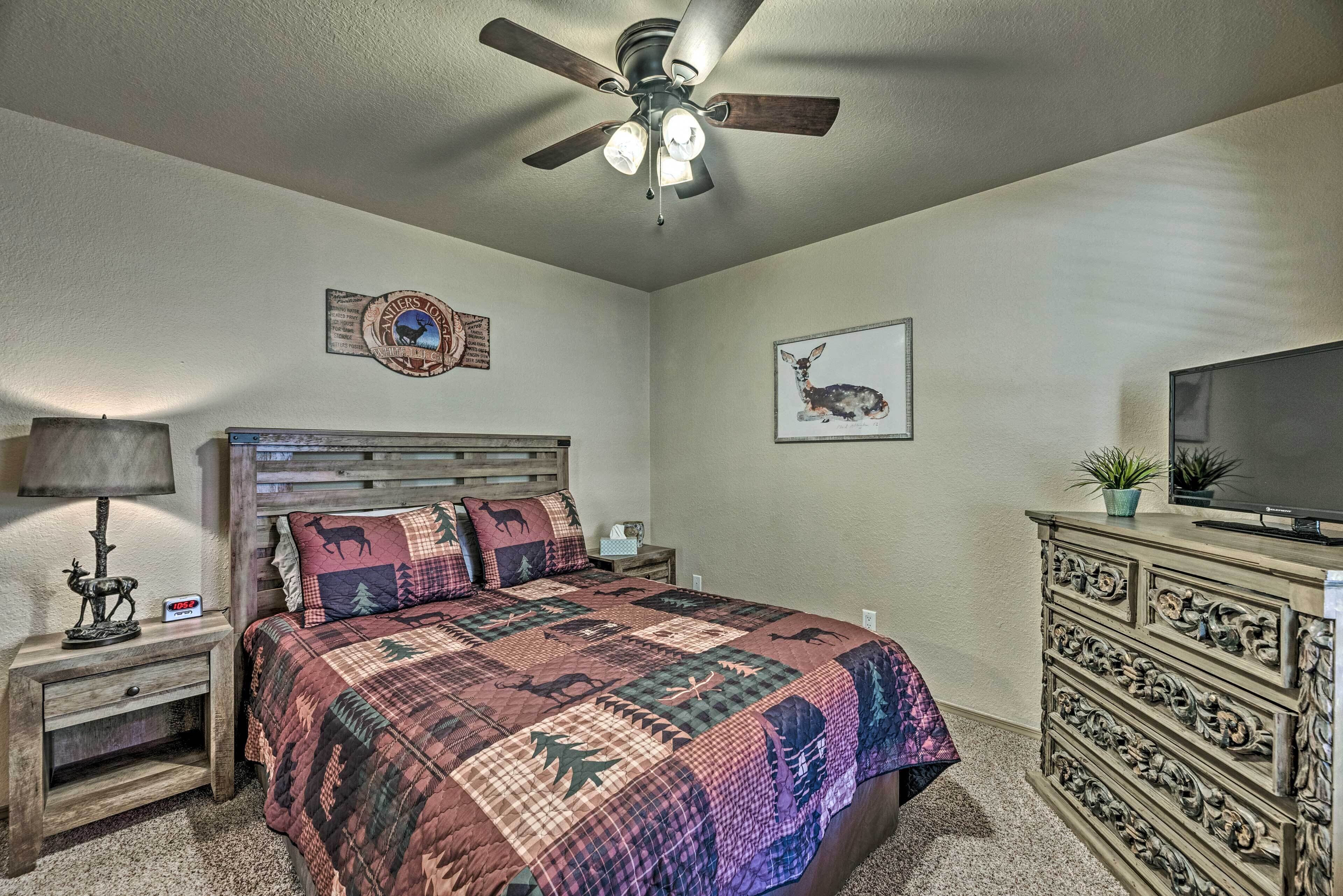 A bedroom with a wooden bed, a ceiling fan, a television, and a dresser.