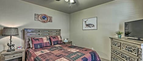 A bedroom with a wooden bed, a ceiling fan, a television, and a dresser.