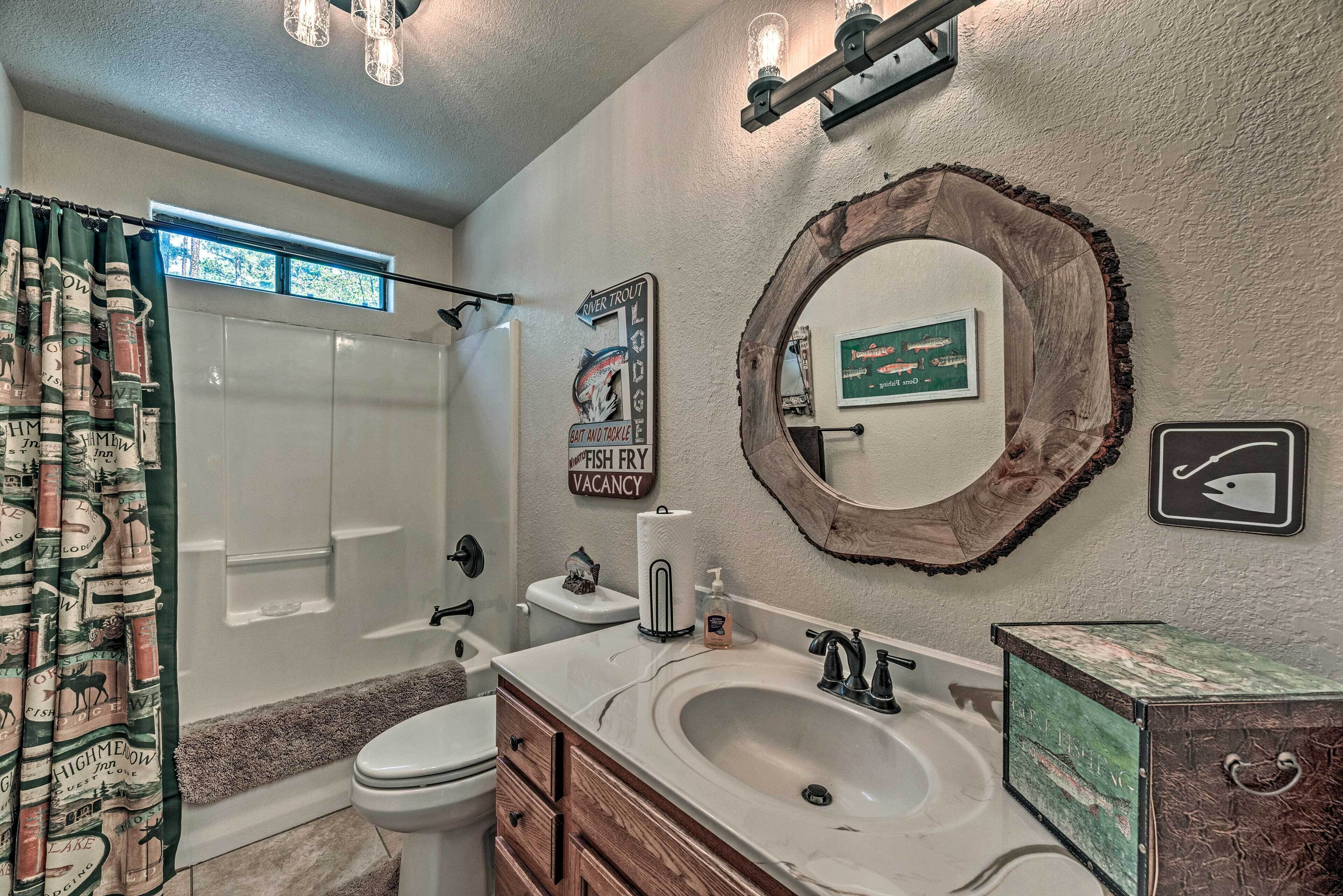 Une salle de bain avec douche, toilettes, lavabo et meuble-lavabo. Il y a des panneaux sur le mur, dont un qui indique « Kimmer Trout Lodge » et un autre qui indique « Chambres disponibles ».