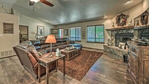 A spacious living room with a leather sectional sofa, a fireplace, and a stone accent wall. - Wooded Ruidoso Hideaway w/ Deck: Ski, Hike & Golf! (Ruidoso)