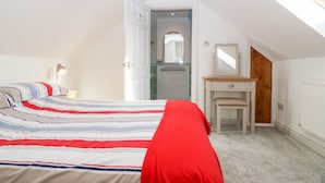 Ein Schlafzimmer mit Bett, Kommode, Spiegel und Dachfenster.