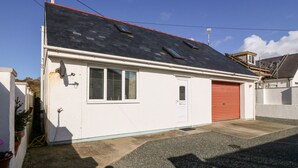 Ein eingeschossiges Haus mit roter Garagentür, einem kleinen Fenster mit Fensterlädchen und einer Satellitenschüssel an der Seite.