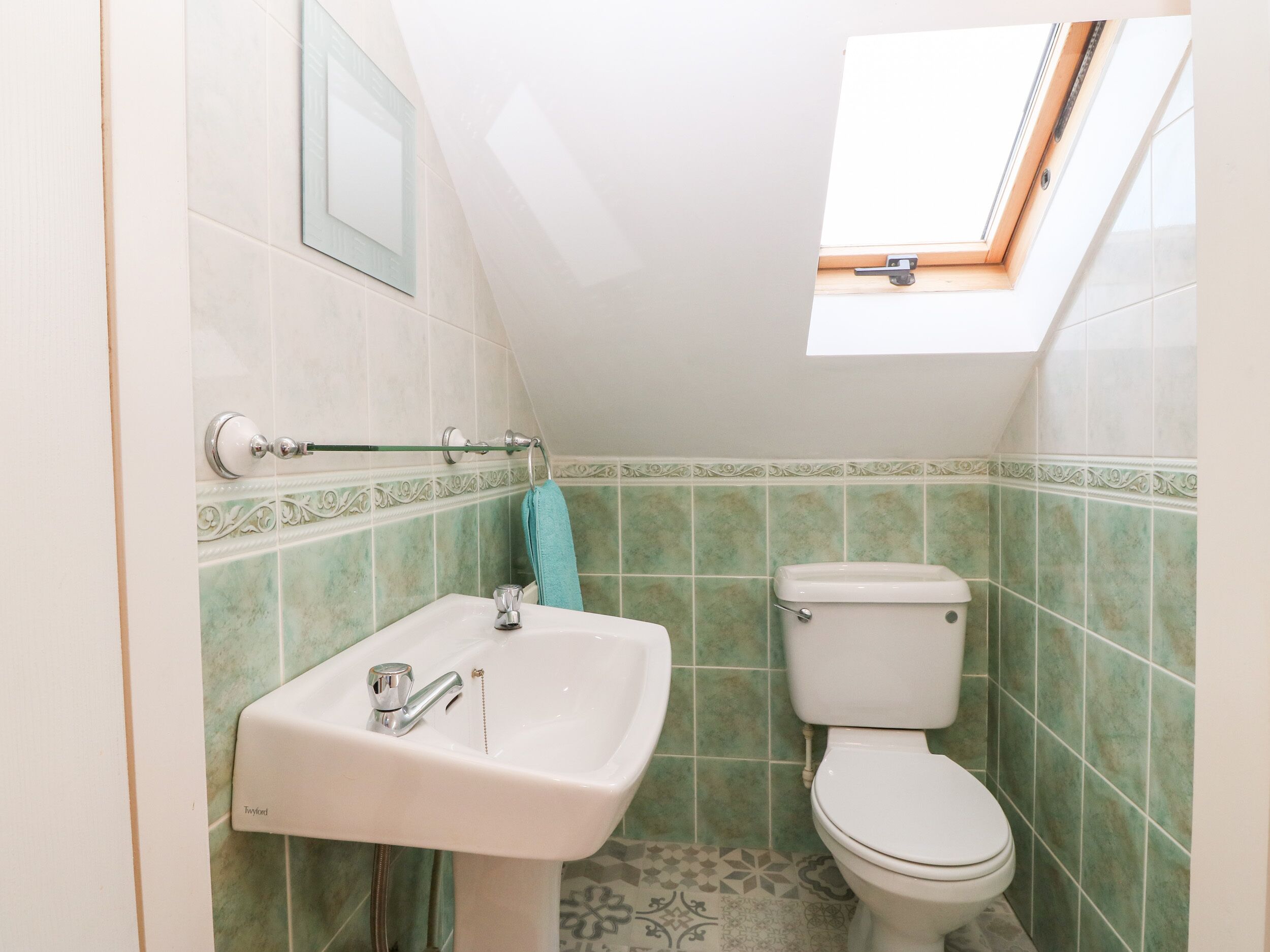 Un baño con tragaluz, lavabo e inodoro.
