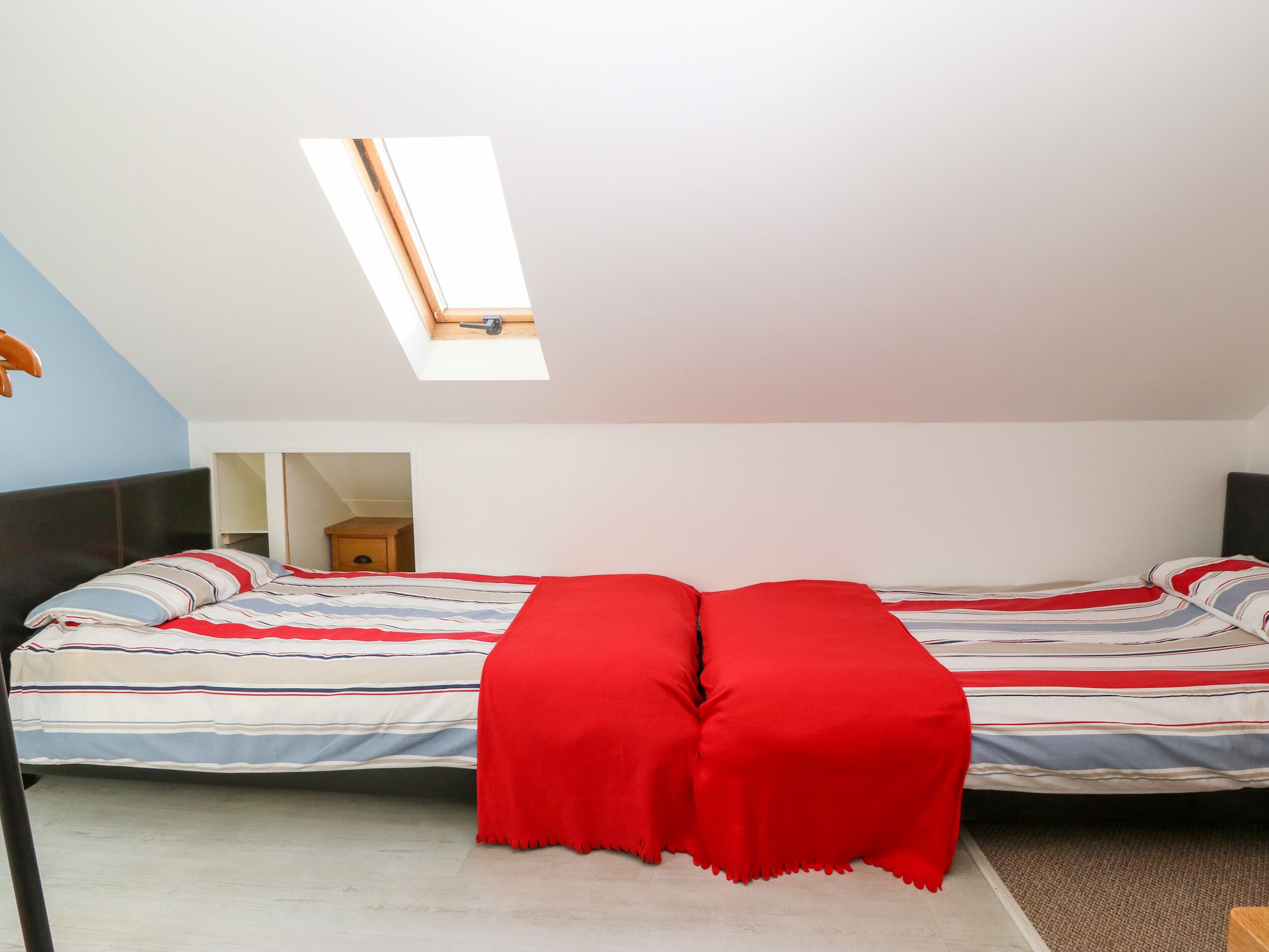A bedroom with a bed, a skylight, and a wardrobe.