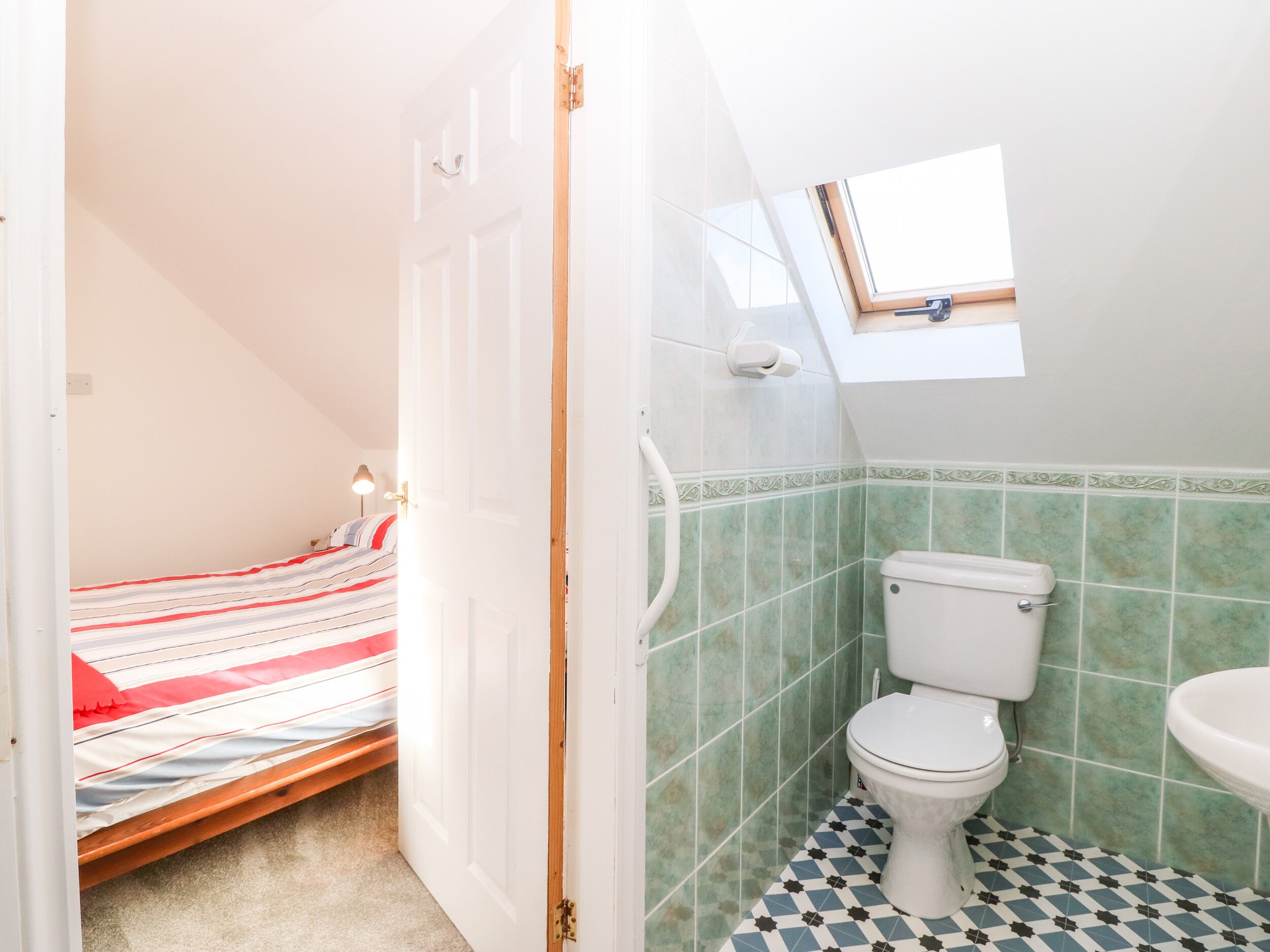 A small, compact room with a bed, a toilet, and a sink.