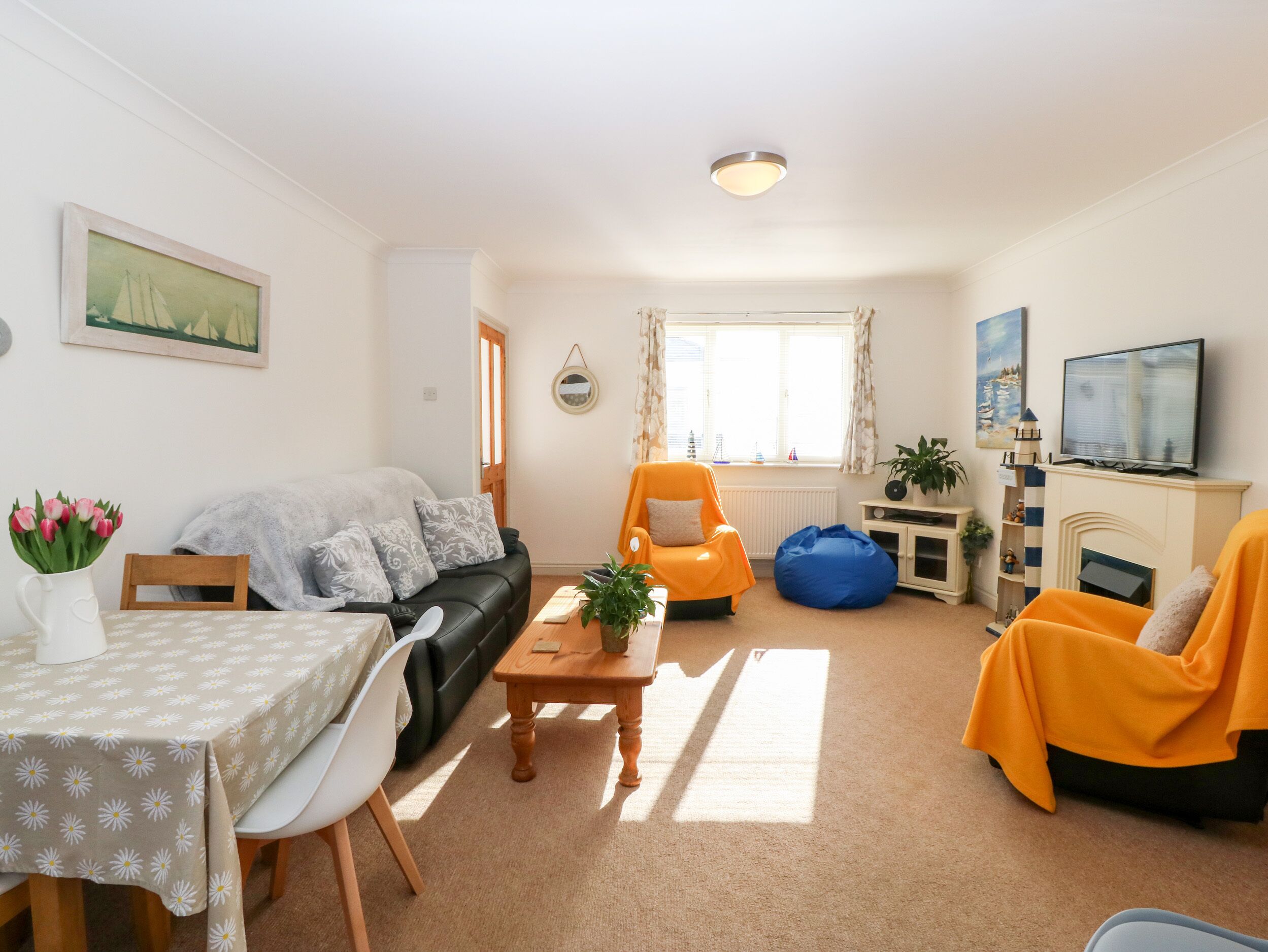 A cozy living room with a sofa, a coffee table, a dining table with chairs, and a television.