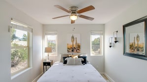 A bedroom with a large bed, a ceiling fan, and artwork on the walls. - Peaceful Peoria Bungalow w/ Grill & Pool! (Peoria)