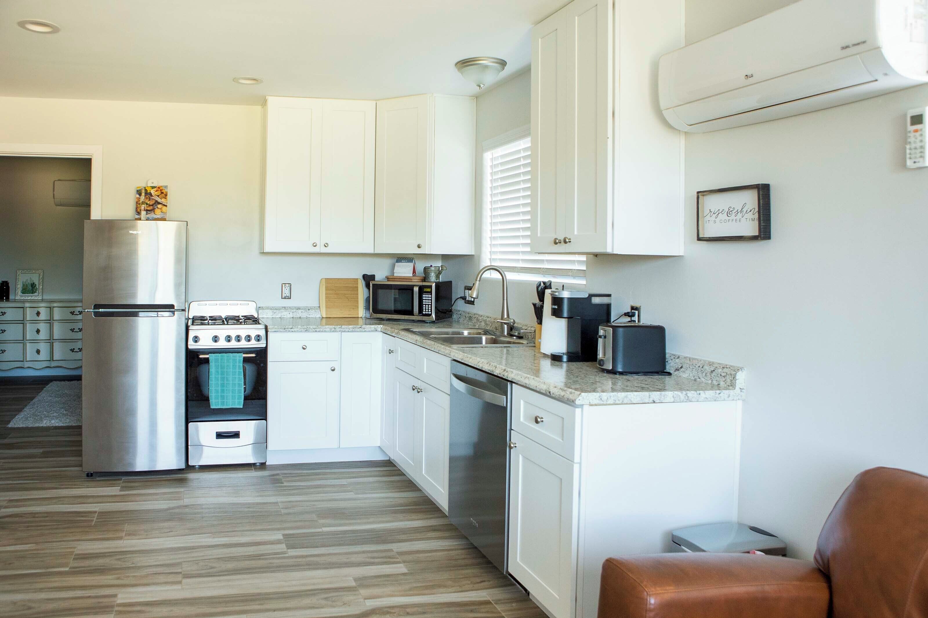 A modern kitchen with white cabinets, stainless steel appliances, and a granite countertop.