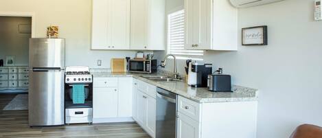 A modern kitchen with white cabinets, stainless steel appliances, and a granite countertop.