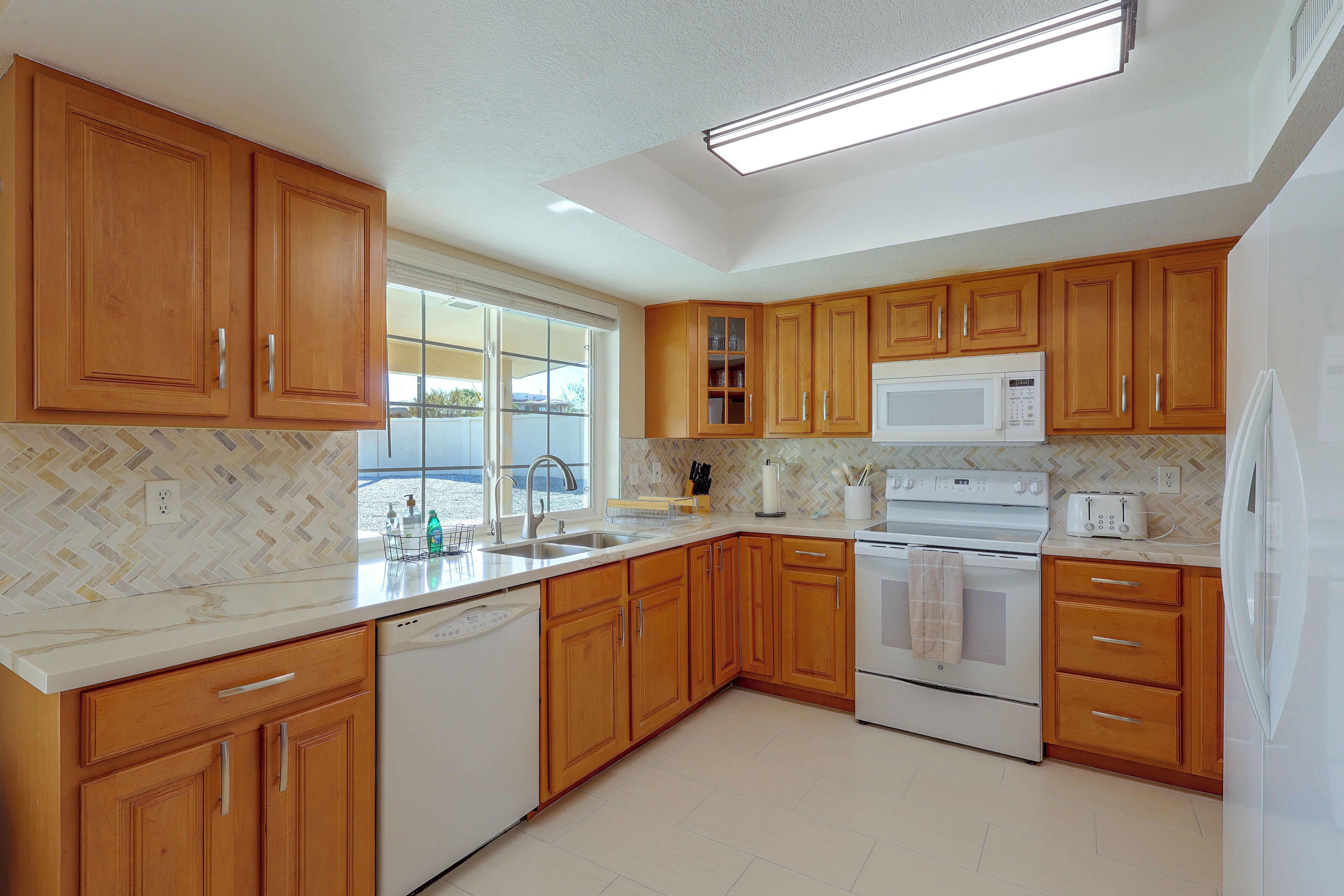 A kitchen with wooden cabinets, a white countertop, a built-in microwave, an oven, and a dishwasher.