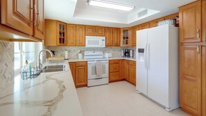 A modern kitchen with wooden cabinets, a white refrigerator, a microwave, and a stove. - 5 Mi to Lake Havasu: Home w/ Yard & Pool (Lake Havasu City)