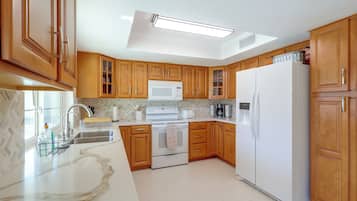 Une cuisine moderne avec des meubles en bois, un réfrigérateur blanc, un four à micro-ondes et une cuisinière.