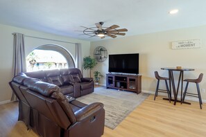 A living room with a leather sofa, a flat-screen TV, a ceiling fan, and a dining area with two chairs. - 5 Mi to Lake Havasu: Home w/ Yard & Pool (Lake Havasu City)