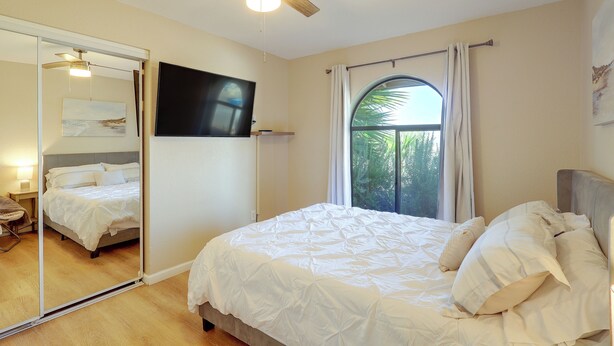 A bedroom with a bed, a ceiling fan, a large mirror, and a window. - 5 Mi to Lake Havasu: Home w/ Yard & Pool (Lake Havasu City)
