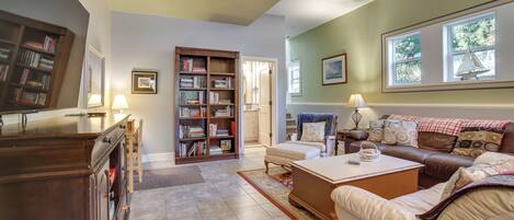 A spacious living room with a large bookshelf, a comfortable sofa set, and a dining table.