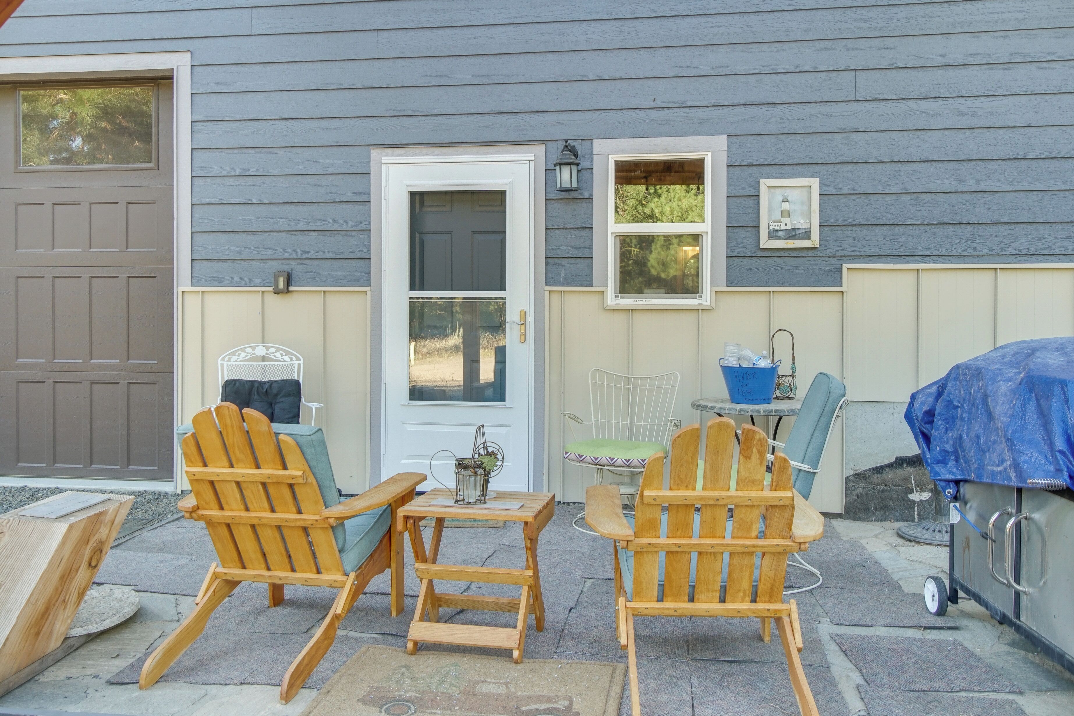 A patio with Adirondack chairs, a small table, and a grill.