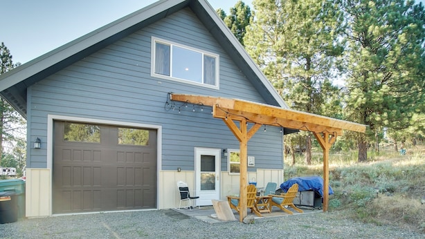 Une maison à deux étages avec un garage, un patio couvert aménagé avec du mobilier d’extérieur et une allée en gravier.