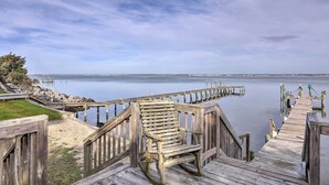 Eine Holzstege, der sich in ruhiges Wasser erstreckt, mit blauem Himmel.