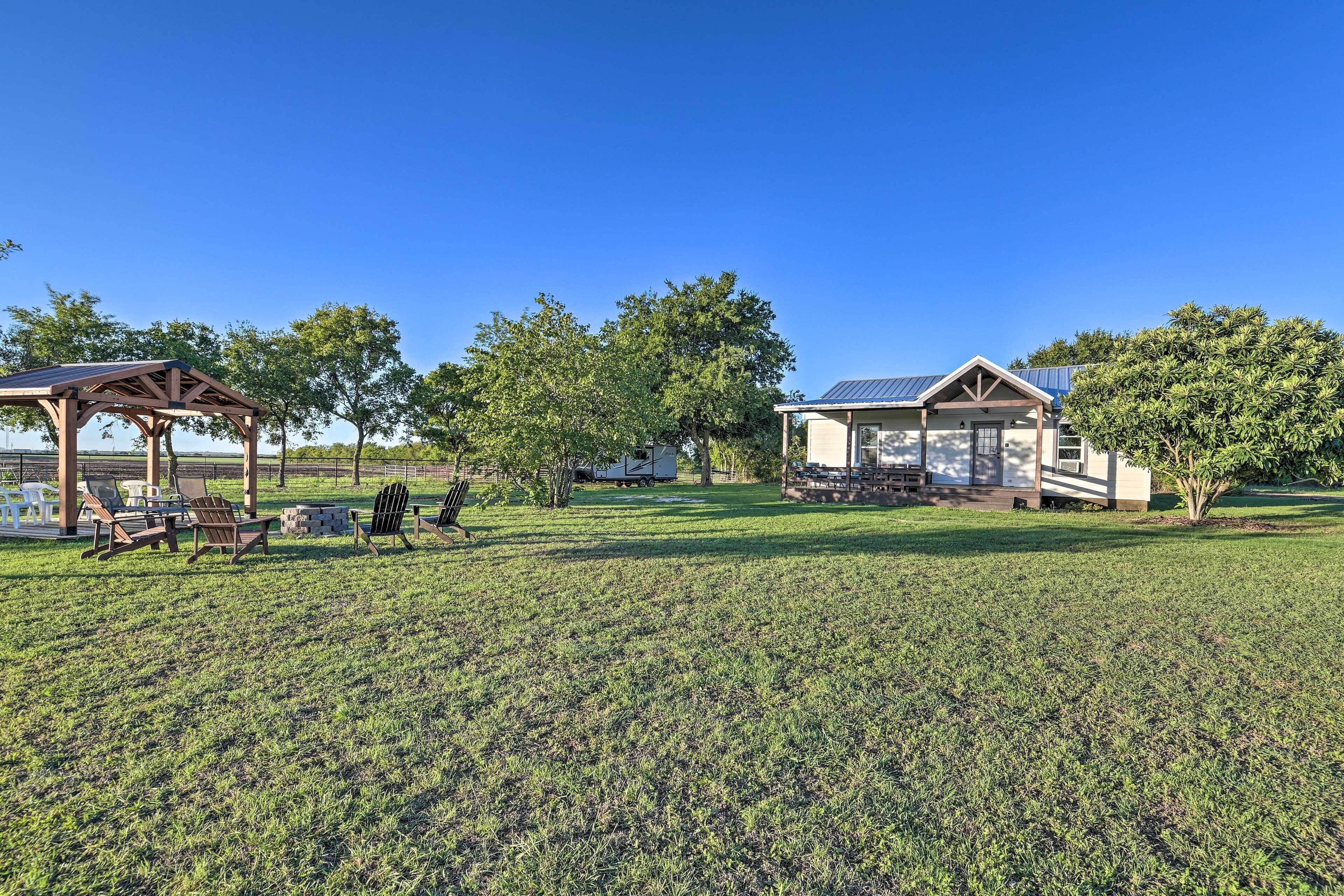 A grassy area with a gazebo, outdoor seating, and a small building with a solar panel.