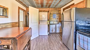 A compact kitchen with wooden cabinets, a stainless steel refrigerator, and a built-in oven.