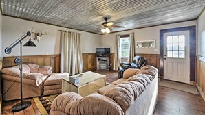 A cozy living room with a ceiling fan, a television, and a leather sofa.