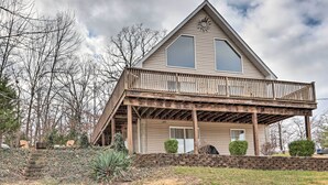A two-story house with a wooden deck, a stone retaining wall, and a small front porch. - Deck, Lake Views! Group Getaway in Osage Beach (Osage Beach)
