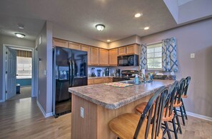Una cocina moderna con encimeras de granito, electrodomésticos de acero inoxidable y armarios de madera.