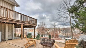 A covered patio with wooden chairs and a metal fire pit, overlooking a residential area. - Deck, Lake Views! Group Getaway in Osage Beach (Osage Beach)