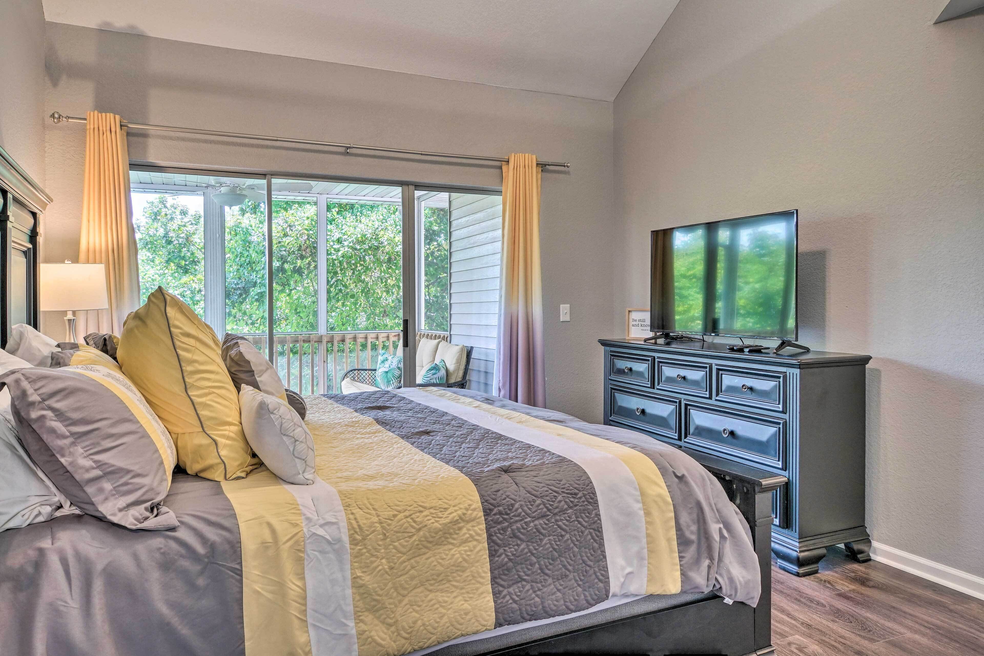 A bedroom with a bed, a dresser, a television, and a window with curtains.
