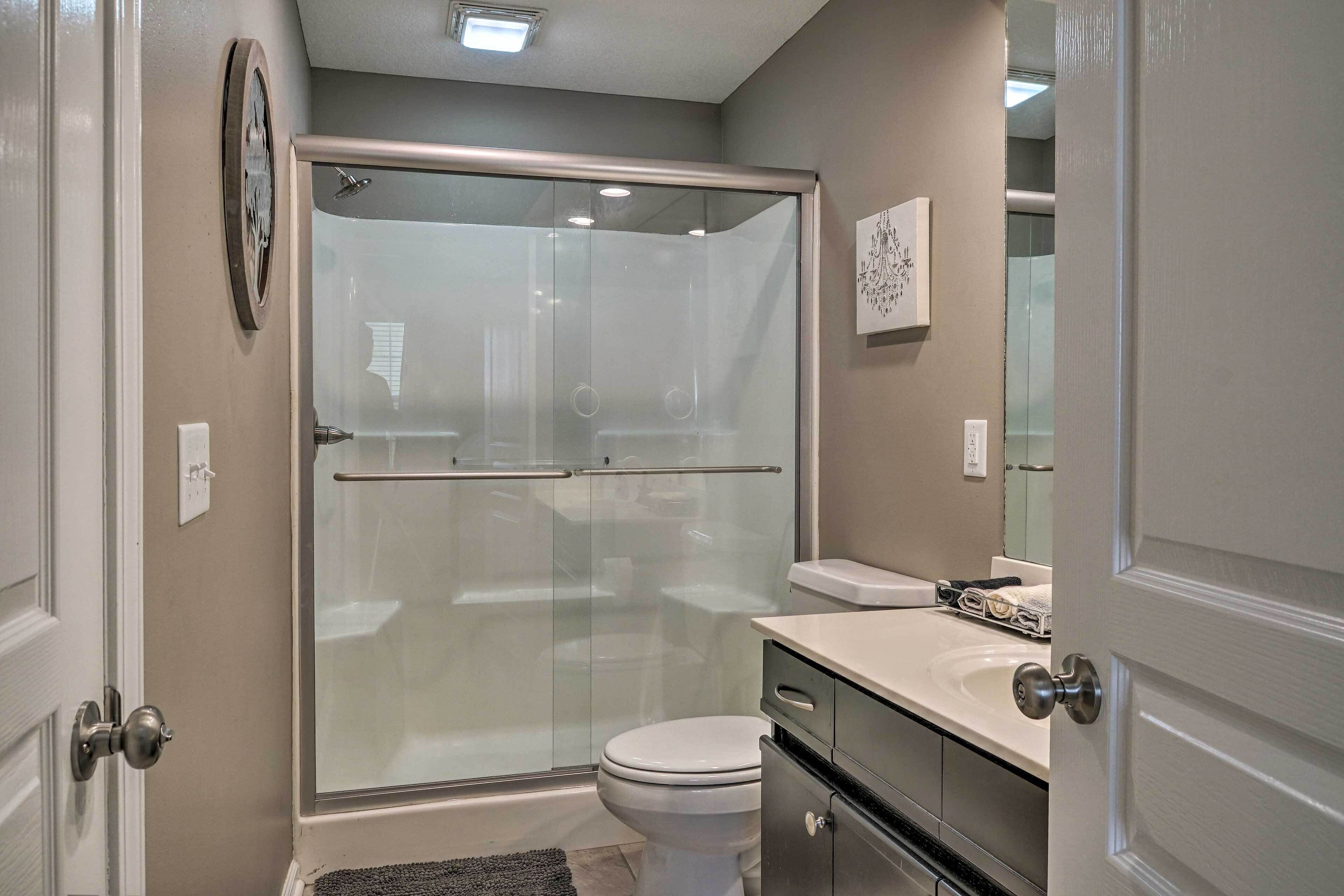 A bathroom with a glass-enclosed shower, a toilet, and a sink.