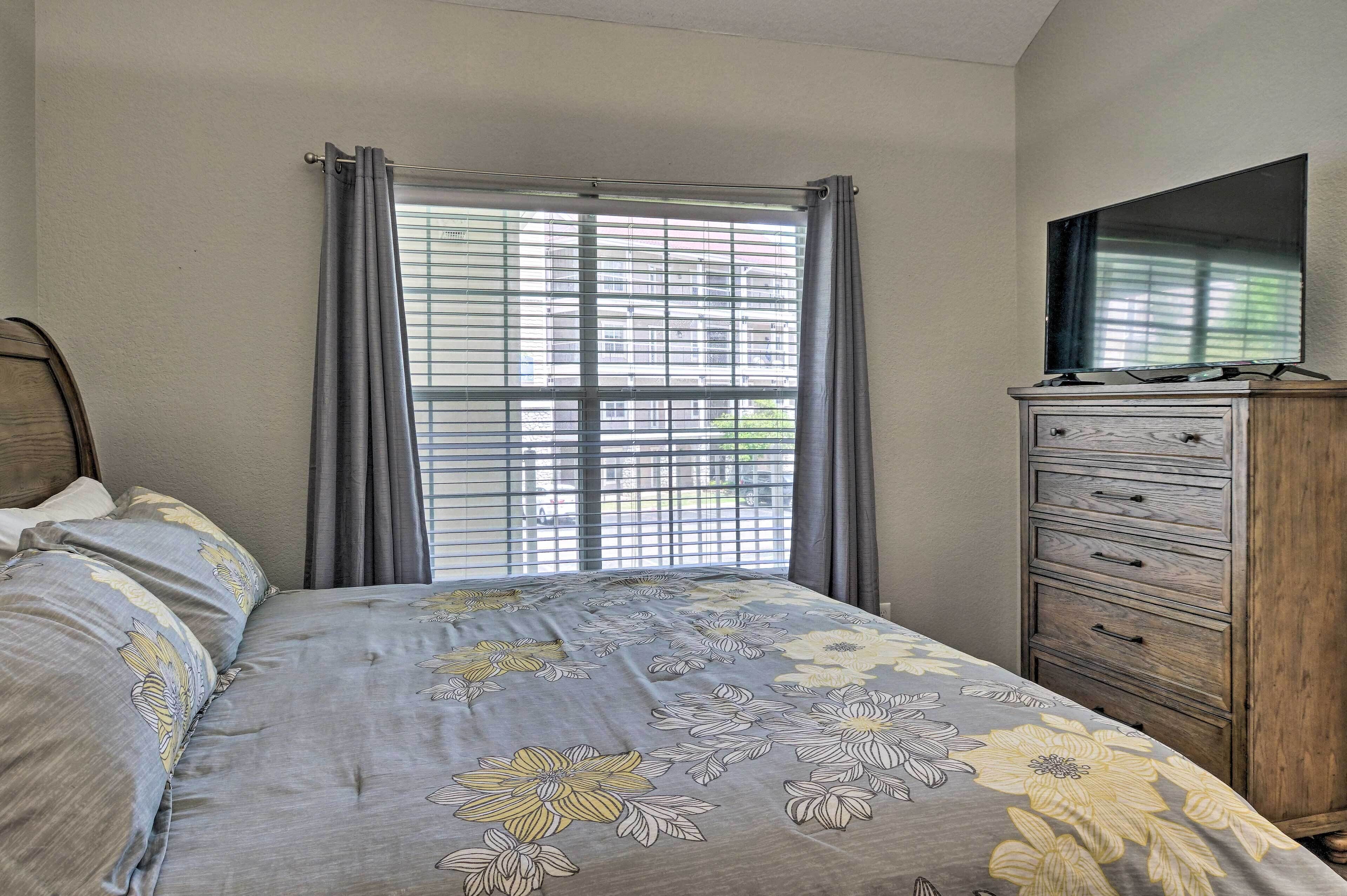 A bedroom with a bed, a dresser, and a TV on the wall.