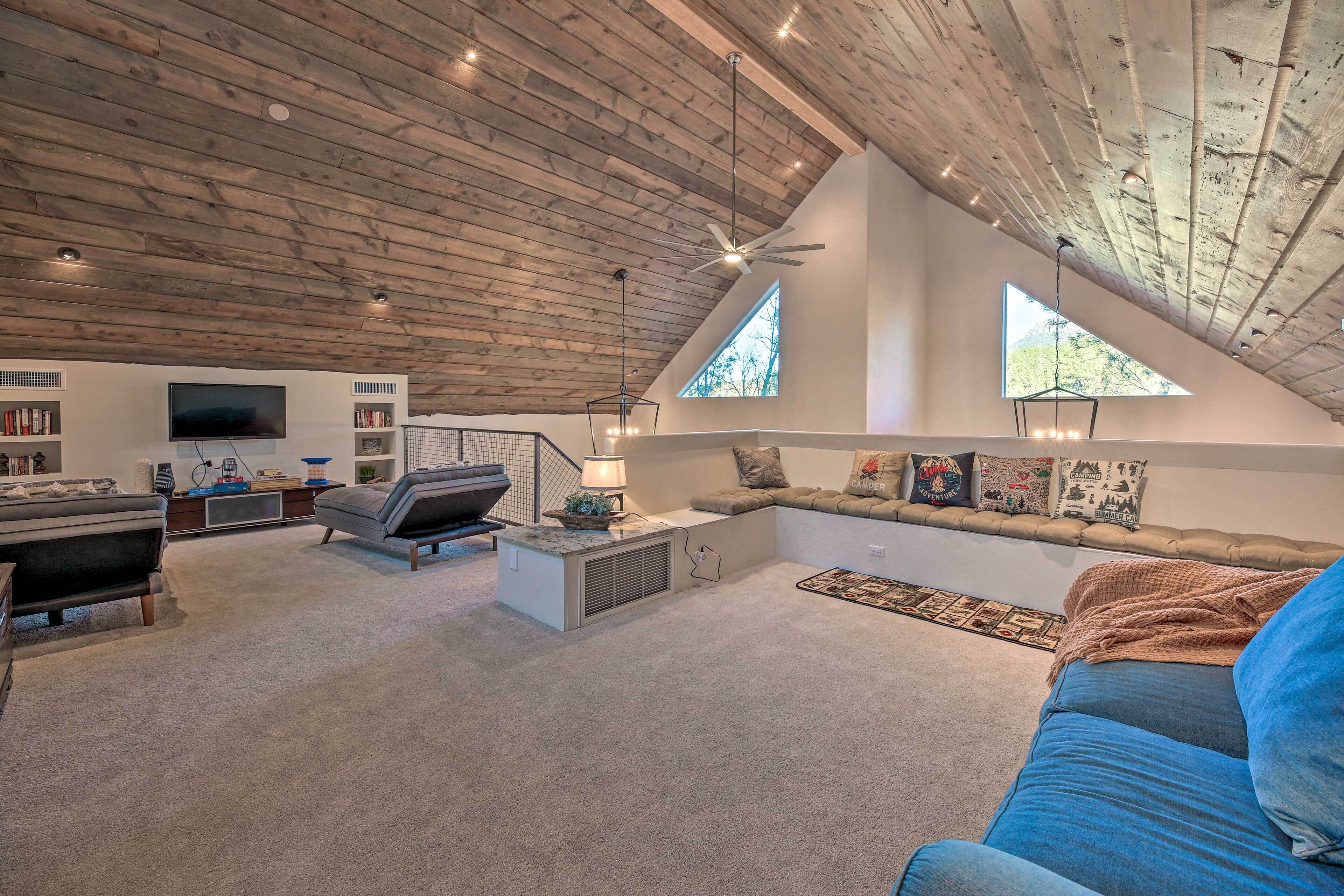 Een ruime woonkamer met een hoge plafond, een inbouw entertainmentunit, een gezellige zithoek en grote ramen die voor natuurlijk licht zorgen.