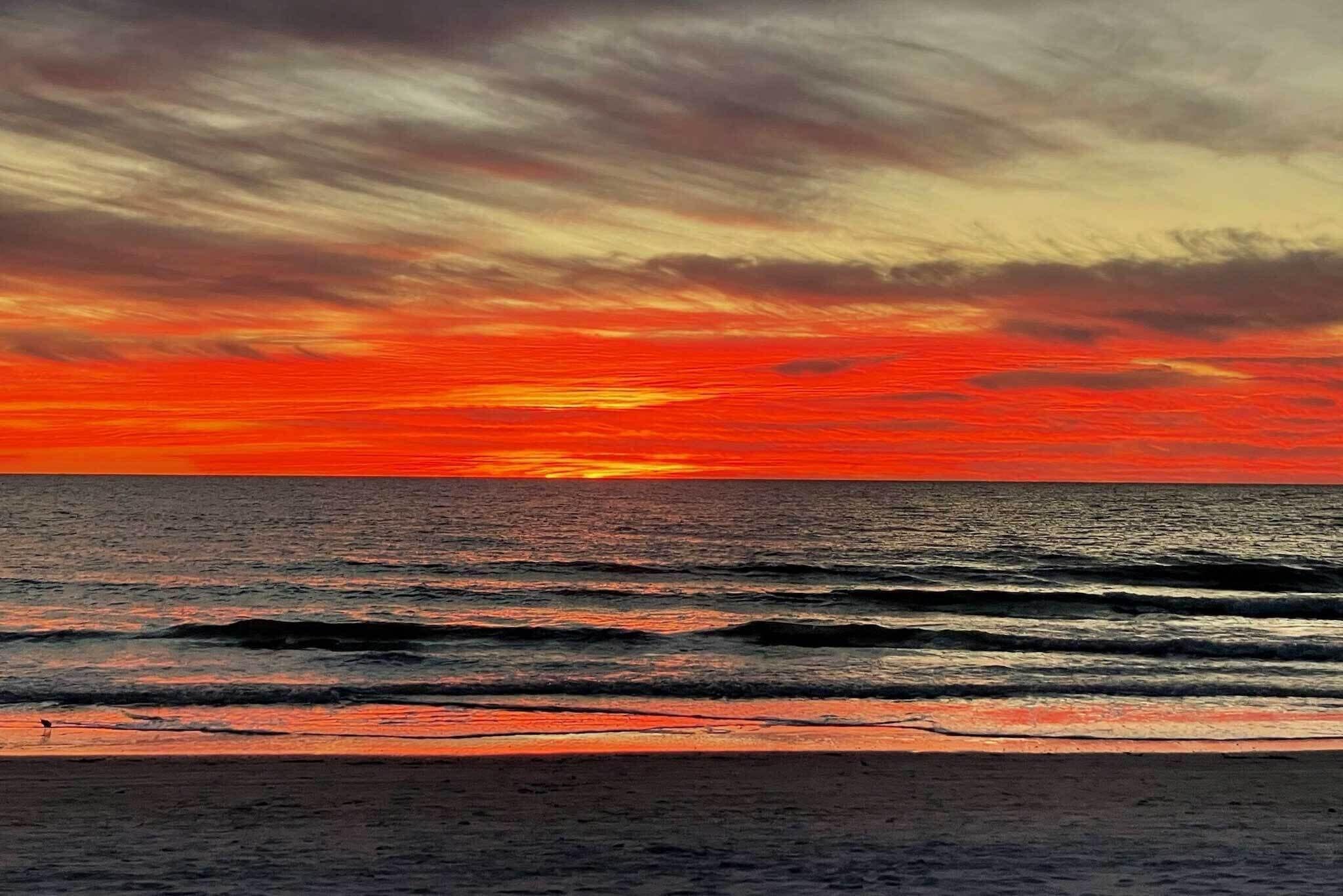 A beach with waves and a sunset.