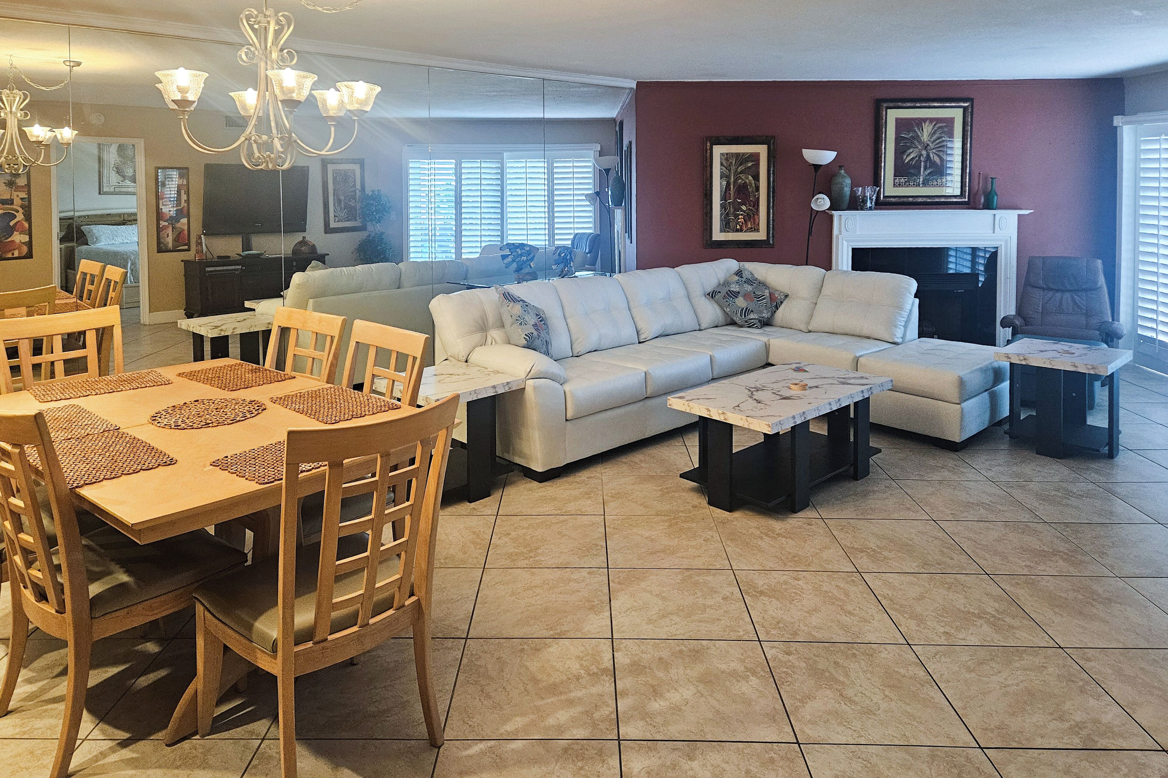 A living room with a sofa, coffee table, dining table with chairs, and a fireplace.